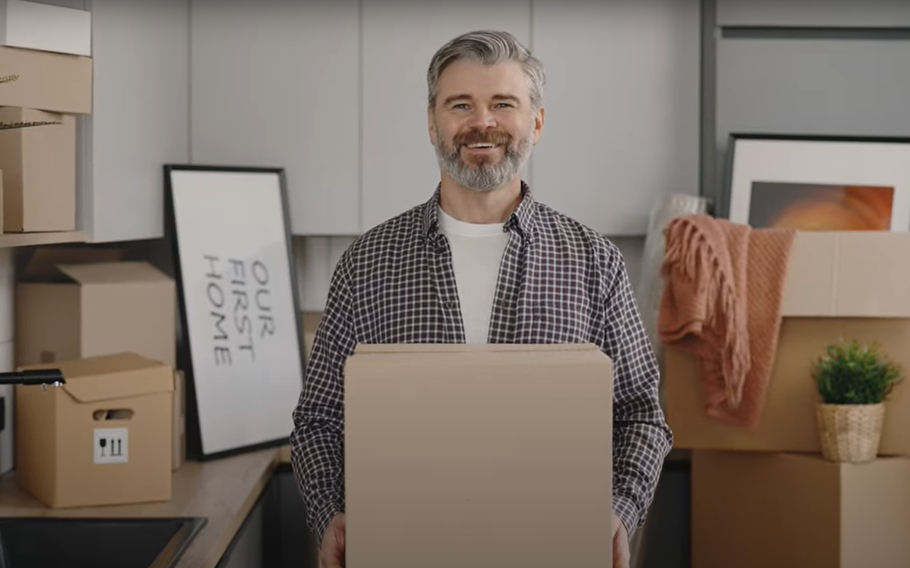 A man smiling holding a cardboard box