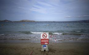 A sign reading "swimming prohibited" sits on a beach with high levels of pollution the morning after a storm passed through Marseille, southern France, Thursday, Aug 18, 2022.