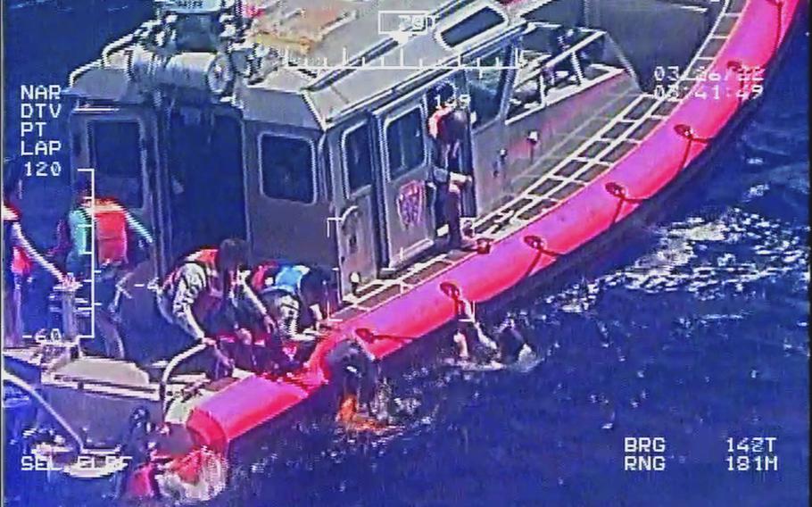 Responders from Guam Fire Department pull crew members out of the water after their catamaran capsized in the Philippine Sea on March 27, 2022.