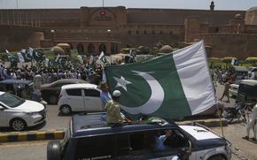 Demonstrators ride cars and march, and many wave Pakistan flags.