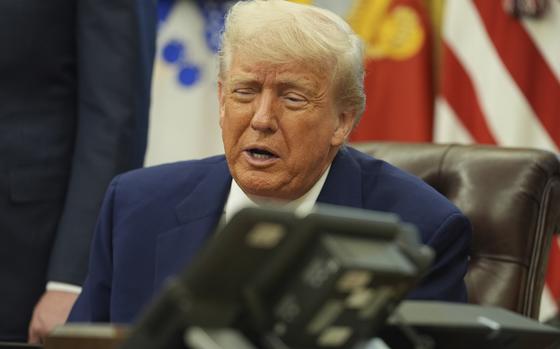 Donald Trump seen in-focus speaking behind an out-of-focus landline phone in the foreground.
