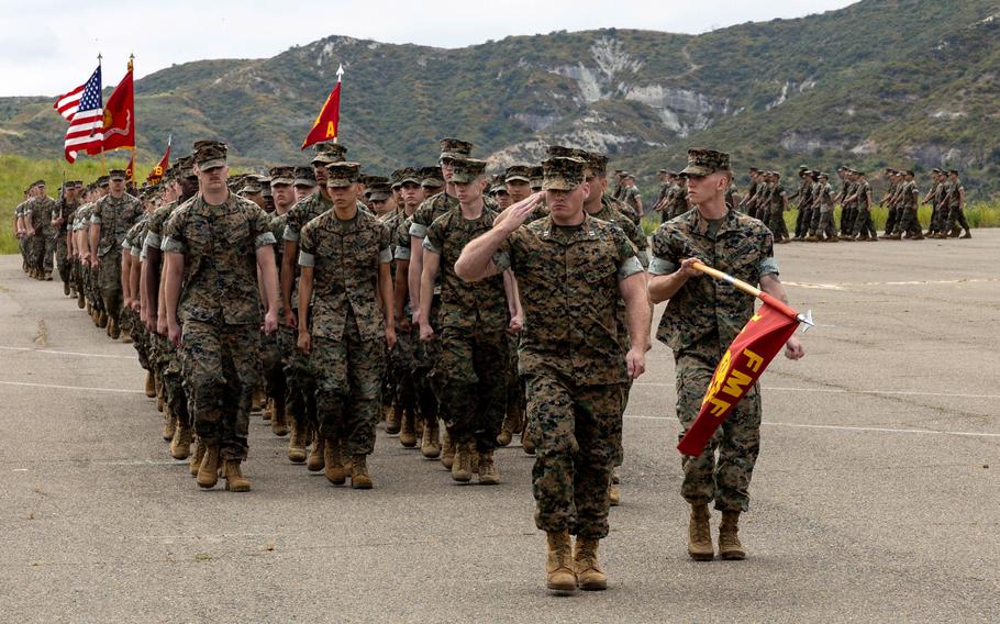 U.S. Marines with 1st Marine Division march in formation during a change of command ceremony at Camp Pendleton, Calif., June 8, 2023. The Corps is easing restrictions on reenlistment requirements for those not progressing through the ranks, which means Marines who have been eligible but have repeatedly been passed over for promotion can now reenlist. 
