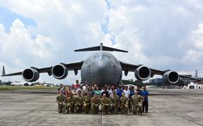 U.S. Airmen assigned to the 21st Airlift Squadron and the 860th Maintenance Squadron pose with humanitarian aid recipients on a flight line at La Aurora International Airport, Guatemala, June 9, 2025. As part of the Denton program, a C-17 Globemaster III aircrew assigned to Travis Air Force Base, California delivered approximately 55,000 pounds of humanitarian aid donated by Non-Governmental Organizations to El Salvador and Guatemala, supporting communities in need. (U.S. Air Force photo by 2nd Lt. Yasmeen Joachim Jordan)