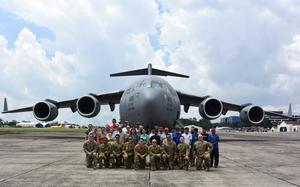 U.S. Airmen assigned to the 21st Airlift Squadron and the 860th Maintenance Squadron pose with humanitarian aid recipients on a flight line at La Aurora International Airport, Guatemala, June 9, 2025. As part of the Denton program, a C-17 Globemaster III aircrew assigned to Travis Air Force Base, California delivered approximately 55,000 pounds of humanitarian aid donated by Non-Governmental Organizations to El Salvador and Guatemala, supporting communities in need. (U.S. Air Force photo by 2nd Lt. Yasmeen Joachim Jordan)