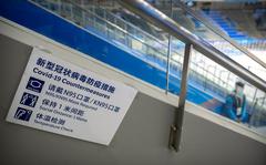 A staff member stands near a sign outlining COVID-19 protection measures during the Experience Beijing Ice Hockey Domestic Test Activity, a test event for the 2022 Beijing Winter Olympics, at the National Indoor Stadium in Beijing, on Nov. 10, 2021.  