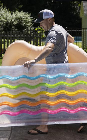 Karl Tradewell brings pool floats to the renters. He’s booked the pool 45 times this summer and August has yet to swelter. 