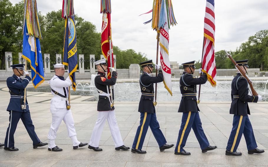 Troops from various military services carrying flags. 