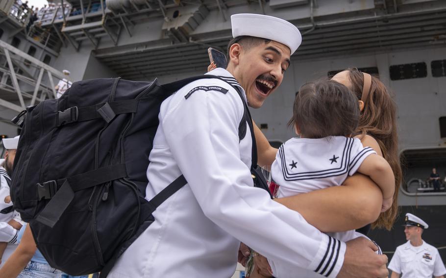 A sailor looks at a baby with excitement.