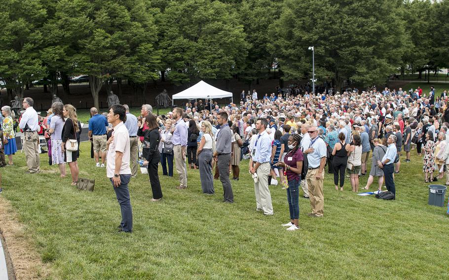 Hundreds of people attending an event at the Korean War Memorial in Washington, D.C., on Tuesday, July 26, 2022, stand facing the American flag during the playing of the National Anthem.