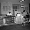 A black and white photo of a meat section at a commissary, with two women standing in front of a counter.