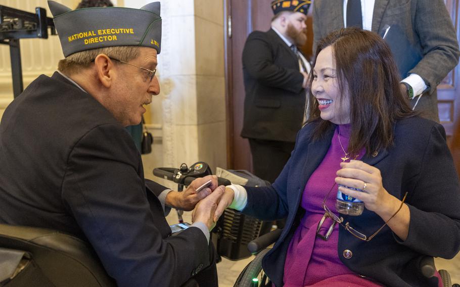 A man and a woman sitting on wheelchairs and shaking hands.