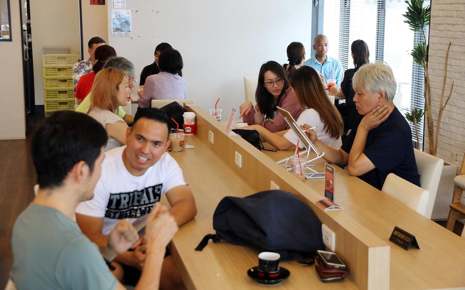 Members of the U.S. Army's 10th Support Group at Torii Station chat with their Japanese neighbors at the Segafredo coffee shop in Yomitan, Okinawa, Tuesday, June 20, 2023.