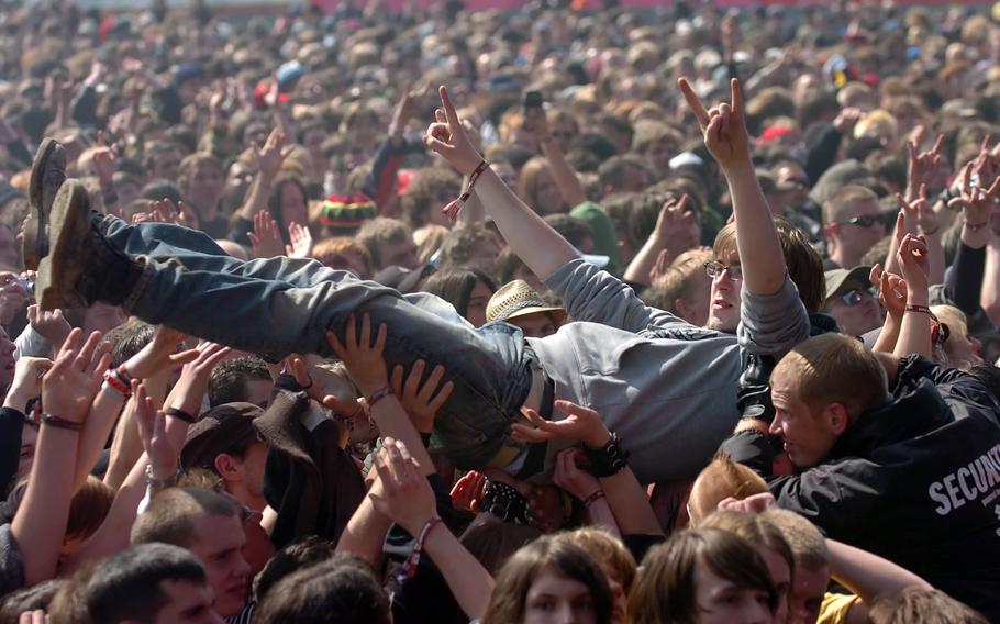A concertgoer gestures the rock and roll sign with both hands while crowd surfing.