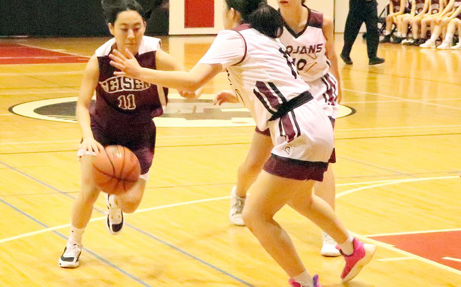 Seisen's Maya Hemmi dribbles against Zama's Lindsey So during Wednesday's Kanto Plain girls basketball game. The Trojans won 38-37, rallying from six points down with two minutes left.