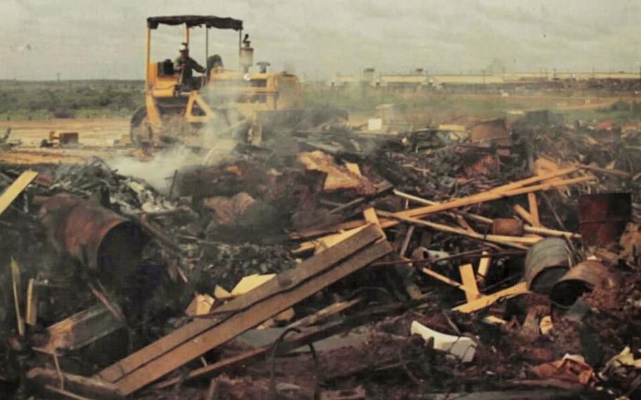 A bulldozer pushes trash into a burn pit.