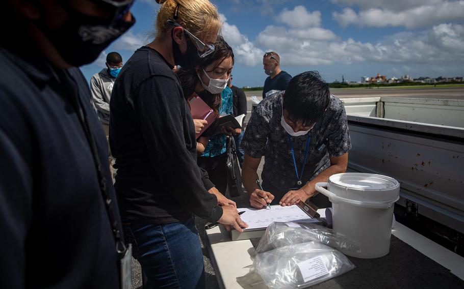 Japanese officials collect samples of treated wastewater at Marine Corps Air Station Futenma, Okinawa, July 19, 2021.