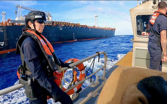 Coast Guard and Drug Enforcement Administration personnel ride on a small boat.