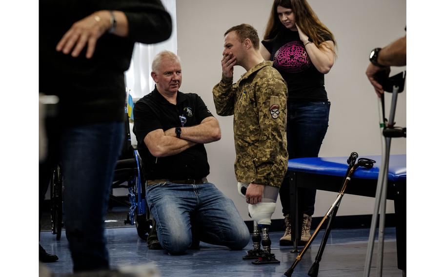 Oleksander Fedun, one of the Ukrainian soldiers getting replacement limbs at Medical Center Orthotics and Prosthetics in Silver Spring, Md., discusses the fit of his new prosthetic legs with Mike Corcoran, left, while volunteer Hanna Ortiz interprets.