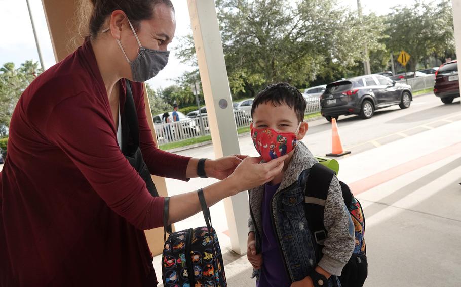 Dolphin Bay Elementary School student Dael Fernandez gets an assist with his mask from his mom Cynthia Fernandez, Wednesday, Aug. 16, 2021 in Miramar, Fla. Masks are still required in public schools in Broward, Palm Beach and six other Florida counties. 