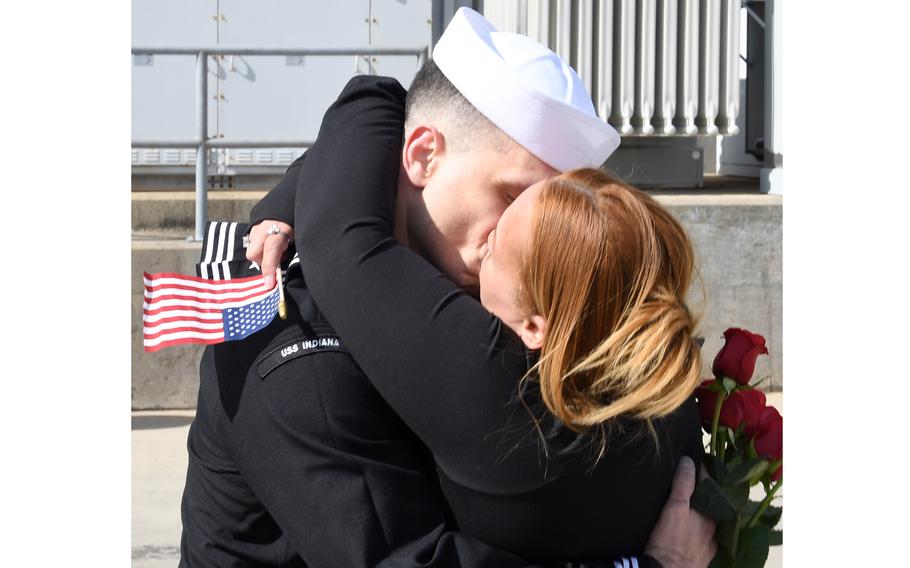 A sailor kisses his wife, who is carrying a U.S. flag.