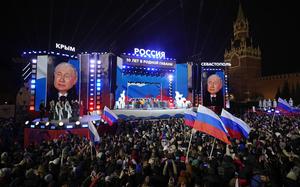 Russian President Vladimir Putin is seen on a screen as he attends a concert in Red Square in Moscow.