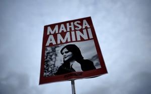 FILE - A woman holds a placard with a picture of Iranian woman Mahsa Amini during a protest against her death, in Berlin, Germany, on Sept. 28, 2022. Iran is responsible for the "physical violence" that led to the death of Mahsa Amini in September 2022 and sparked nationwide protests against the country's mandatory headscarf, or hijab, laws and its ruling theocracy, a U.N. fact-finding mission said Friday, March 8, 2024. (AP Photo/Markus Schreiber, File)