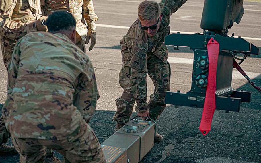 Soldiers load a missile onto an Apache helicopter.
