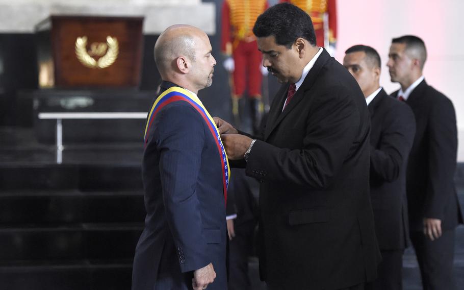 Venezuelan President Nicolas Maduro, right, decorates Gerardo Hernandez, one of the “Cuban Five,” during a ceremony held in front of the coffin with the remains of Simon Bolivar in Caracas on May 5, 2015.