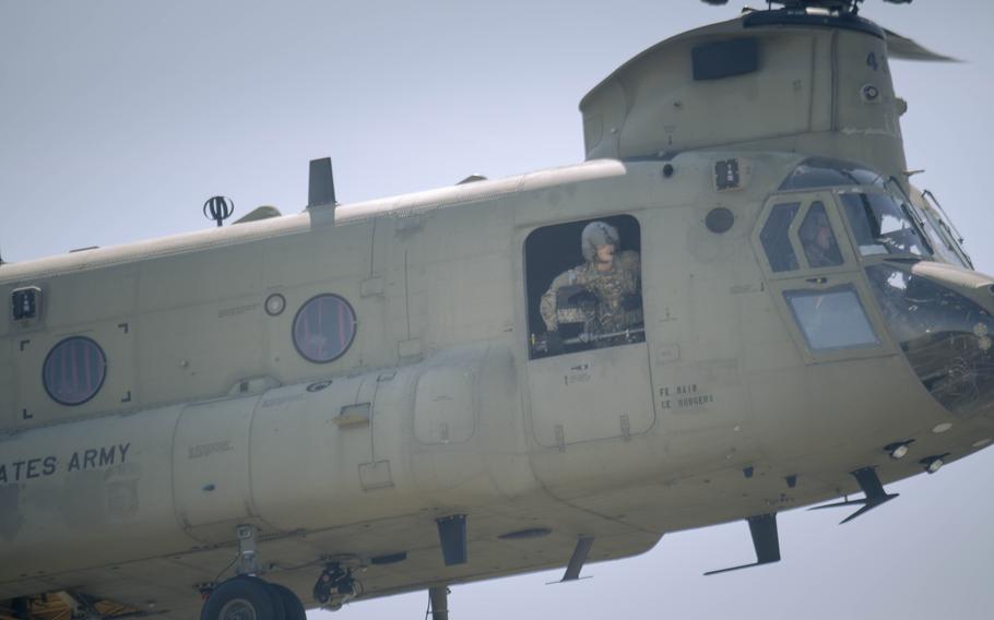 A soldier looks out the door of the in-flight helicopter.