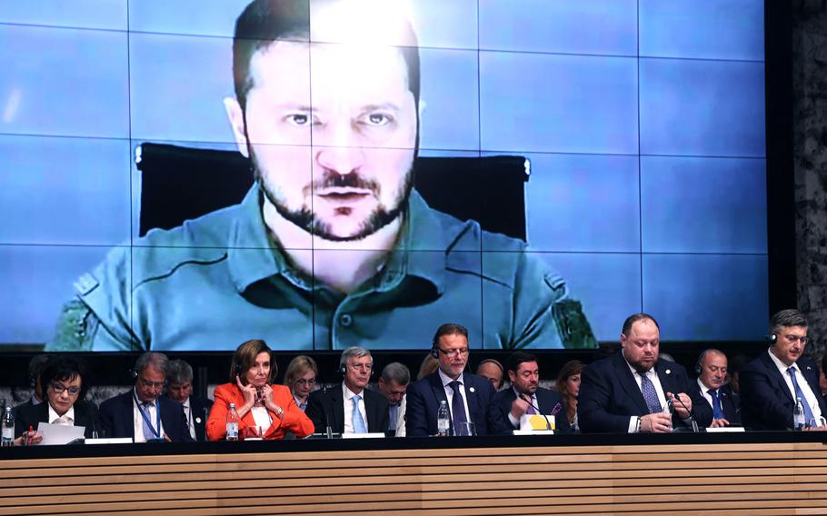 Ukraine President Volodymyr Zelenskyy appears on screens as he speaks via a video link at the opening session of the International Crimea Platform Parliamentary summit, organized by Ukraine and Croatia, in Zagreb, on Oct. 25, 2022. 