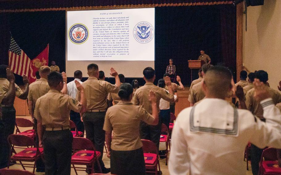 U.S. service members raise their right hand during a naturalization ceremony hosted at the Camp Foster Community Center on Okinawa on April 25, 2022.