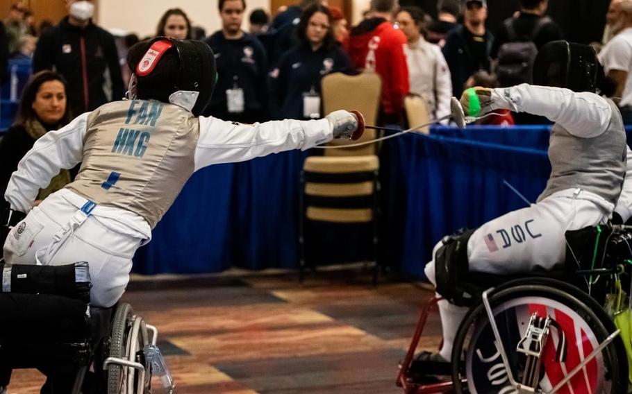 A wheelchair fencer lunges at an opponent, who blocks the move.