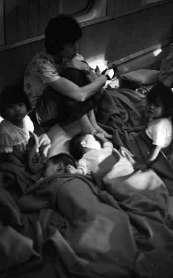 A woman surrounded by infants and other young children.