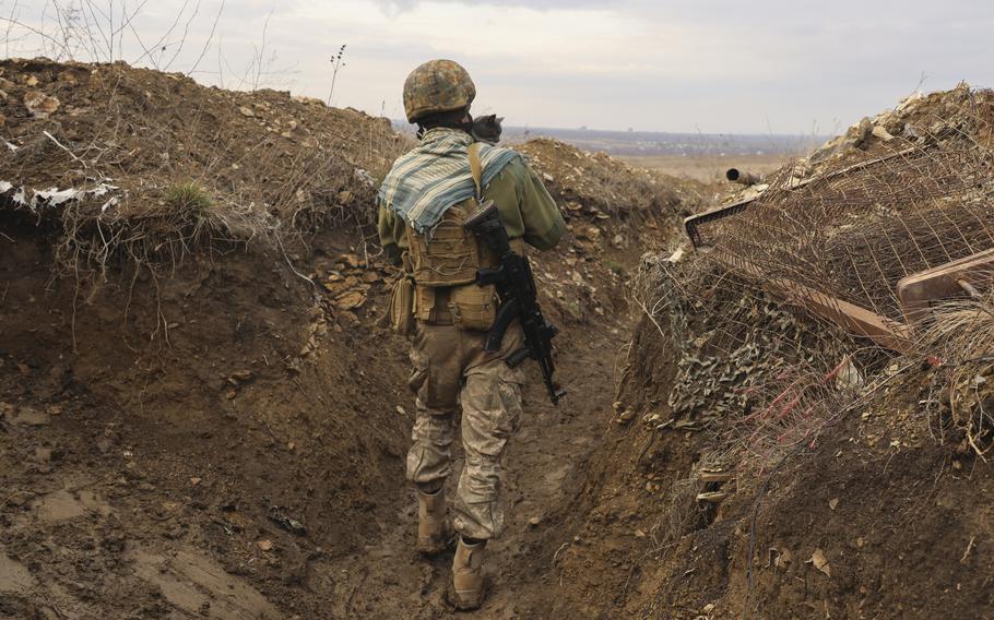 A Ukrainian soldier holds a cat and walks in a trench on the line of separation from pro-Russian rebels near Debaltsevo, Donetsk region, Ukraine, Ukraine Friday, Dec 3, 2021. 