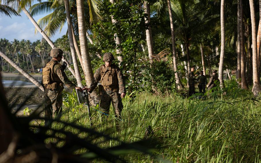 Lance Cpls. Spencer Alvarez and Kaleb Snyder of Marine Rotational Force-Southeast Asia set up a sensor during costal defense training at Kamuning beach in Palawan, Philippines, on Nov. 16.