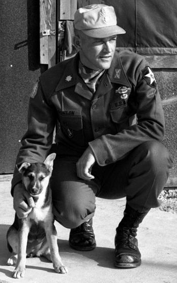 Maj. Roger Donlon, the first Medal of Honor recipient in the Vietnam war, poses outside his headquarters tent at the Advanced Combat Training Academy. With him is the camp’s mascot, “Lieutenant.”