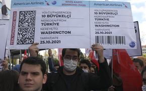 Members of a Turkish group hold a symbolic boarding pass for 10 foreign ambassadors as they stage a protest near the U. S. Embassy in support of Turkey's President Recep Tayyip Erdogan, in Ankara, Turkey, Monday, Oct. 25, 2021. Erdogan last Saturday announced he ordered 10 ambassadors, including those from the US, Germany and France, be declared persona non grata, following a joint statement from the envoys calling for the release of Turkish activist Osman Kavala.  (AP Photo/Burhan Ozbilici)