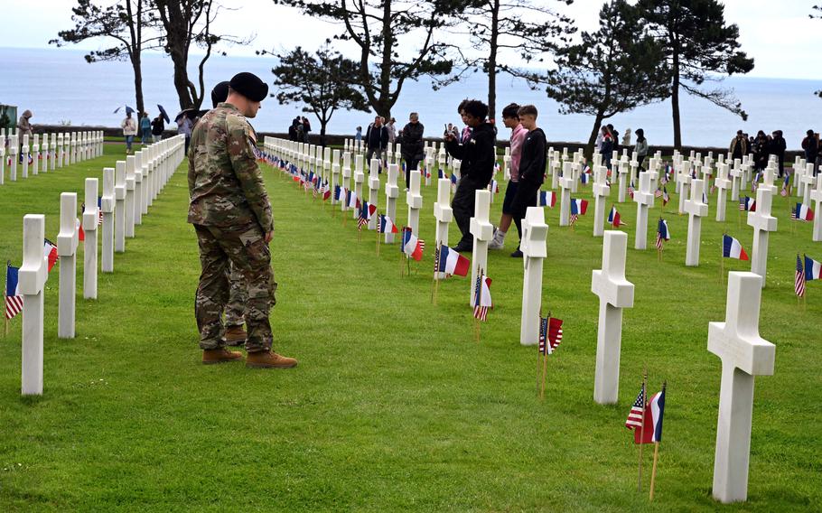 Uniformed troops pay their respects at a cemetery.