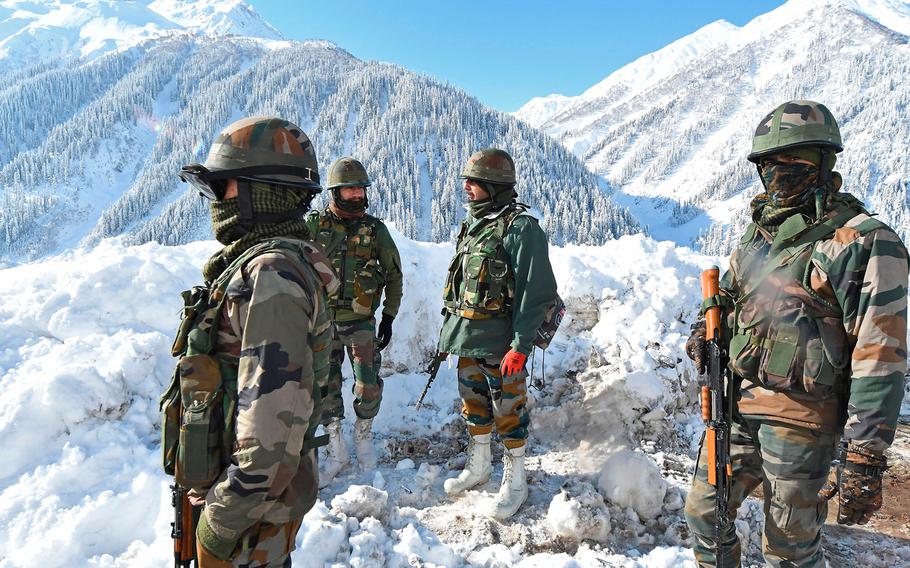 In this photo from Feb. 28, 2021, Indian army soldiers stand on a snow-covered road near Zojila mountain pass that connects Srinagar to the union territory of Ladakh, bordering China. 