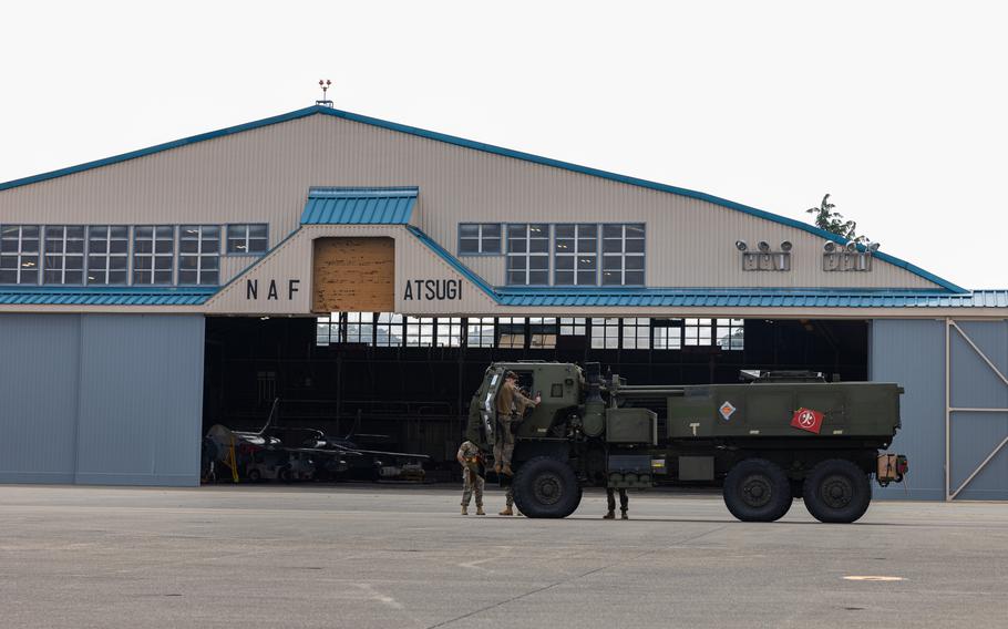 An M142 High Mobility Artillery Rocket System in front of a hanger.