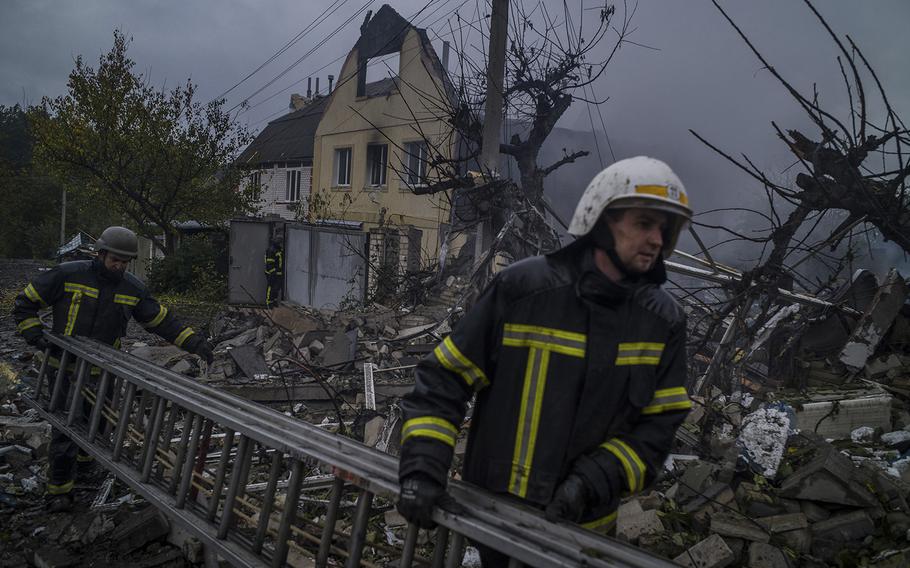 Firefighters work in a house that was destroyed in a rocket strike in Kupiansk on Oct. 10, 2022.