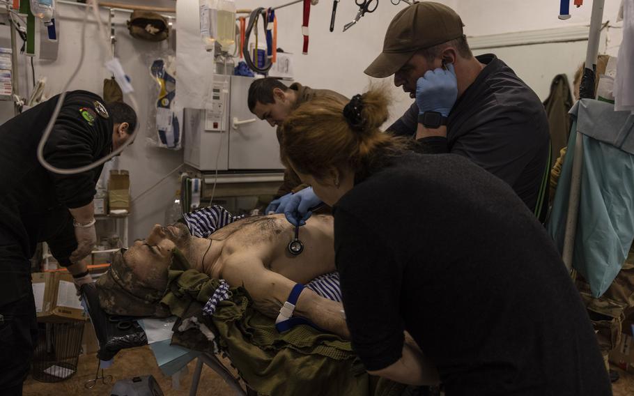 A Ukrainian soldier critically injured in the battle for Bakhmut is treated at a military clinic Feb. 12, 2023, in Donetsk. Oleg Tokarchyk, right, a pediatric orthopedist in civilian life, tells his wife he is working at a hospital far from the front.