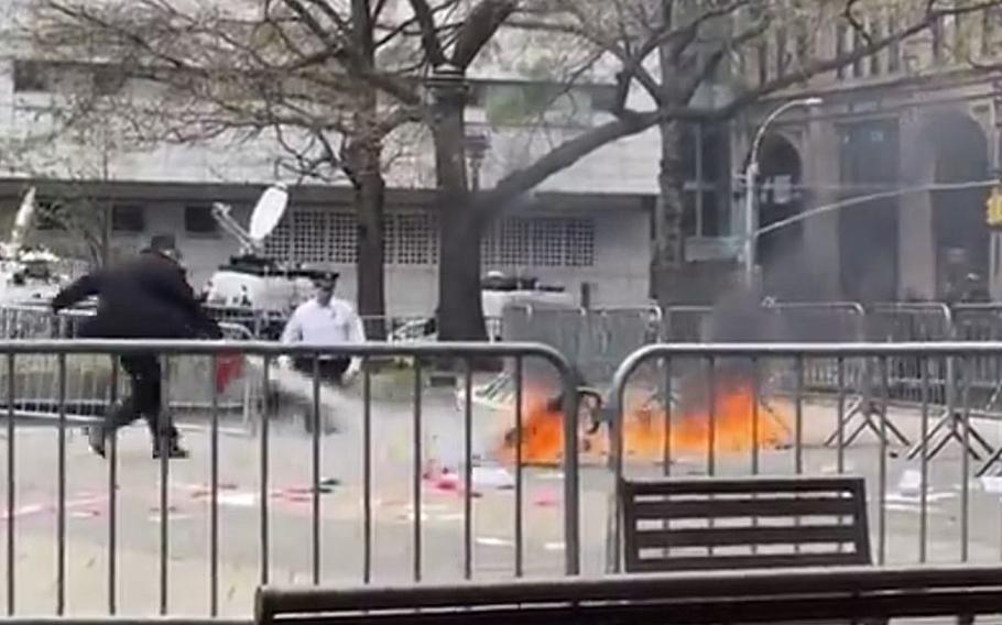 A video screen grab shows a man using a fire extinguisher on a man who set himself on fire near the New York courthouse where former President Donald Trump was seated for a criminal trial in Manhattan.