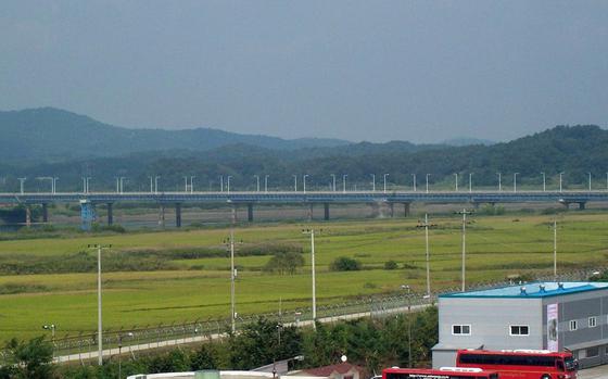 A bridge stretches in front of green hills.