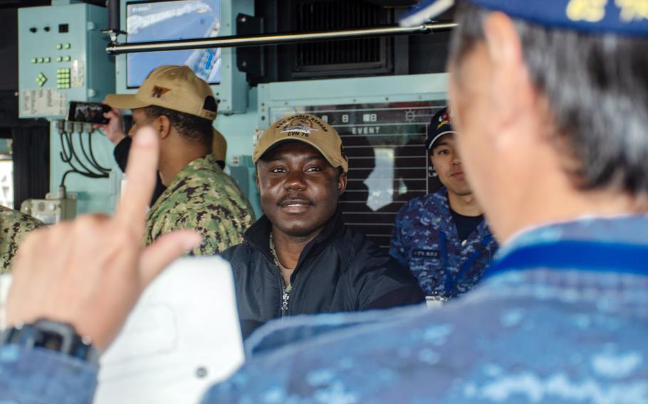 Petty Officer 1st Class Theophilus Nyinaku, a logistics specialist for the USS Ronald Reagan, chats with a JS Izumo sailor during a tour of the Japanese carrier in Yokosuka, Japan, April 2, 2024.