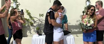 A couple kiss in their triathlon attire. 