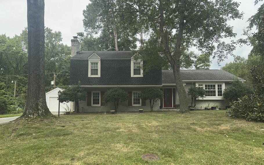 A two-story, suburban home is seen from the street, with a yard and two large trees in front.