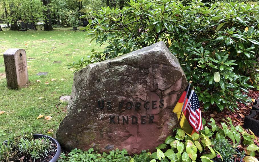 The Kindergraves memorial at Hauptfriedhof Kaiserslautern is decorated with American and German flags. Gravestones mark the burial spots of 451 American infants who died between 1952 and 1971 while their families were stationed in or near Kaiserslautern, Germany.