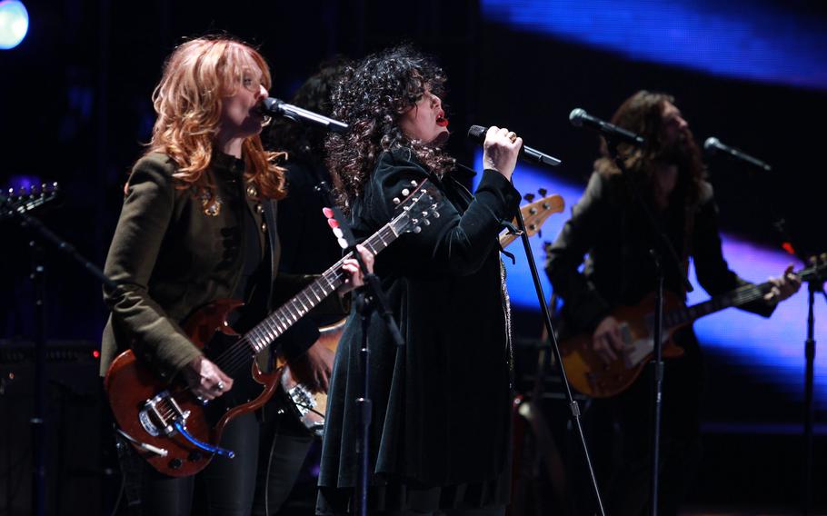 Two musicians play guitar and sing into microphones during a concert.