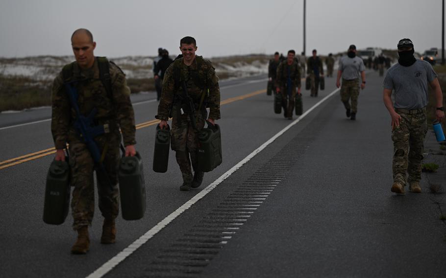 U.S. Air Force special tactics and combat rescue officer candidates carry jerry cans down a stretch of road during an assessment and selection at Hurlburt Field, Fla., on March 22, 2021. 